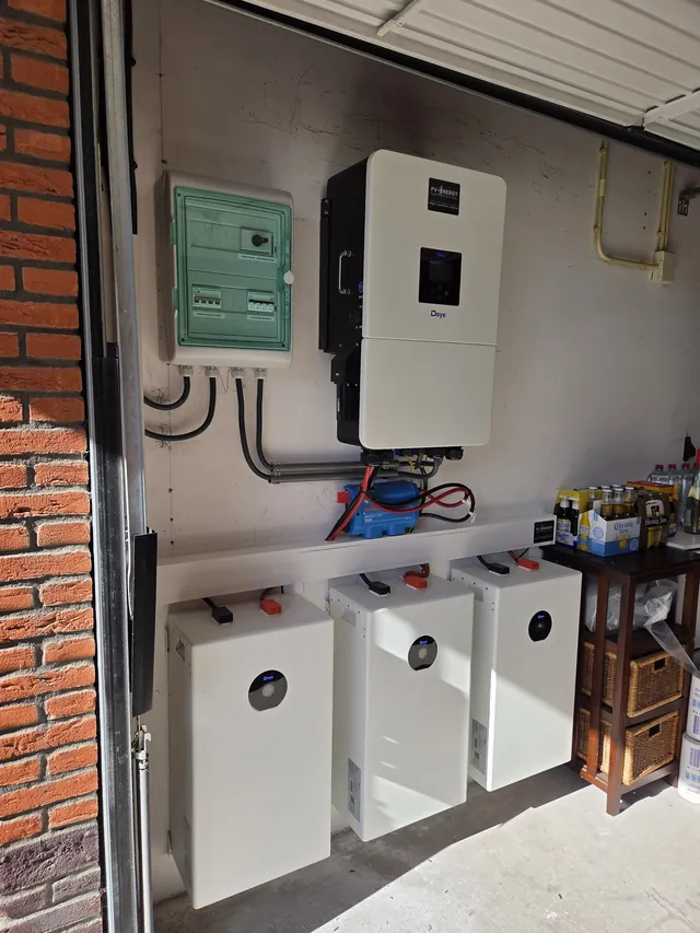 Deye inverter and distribution box in a garage, with three battery modules in a row below.
