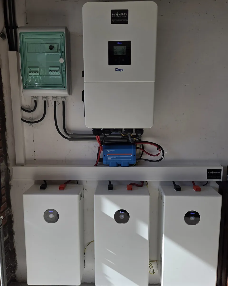 Deye inverter and distribution box in a garage, with three battery modules in a row below.